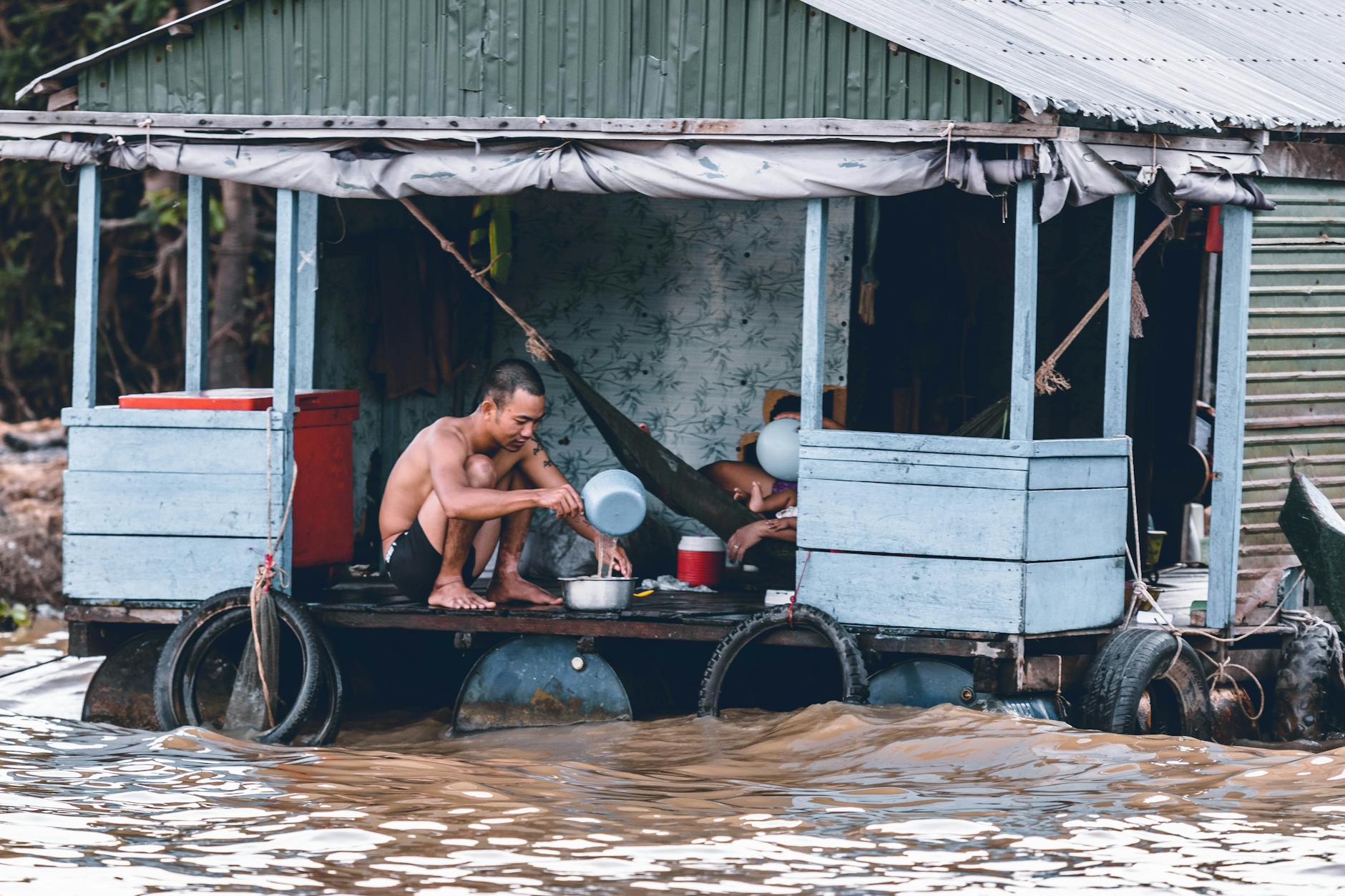 man pouring water from dipper on blue and grey house