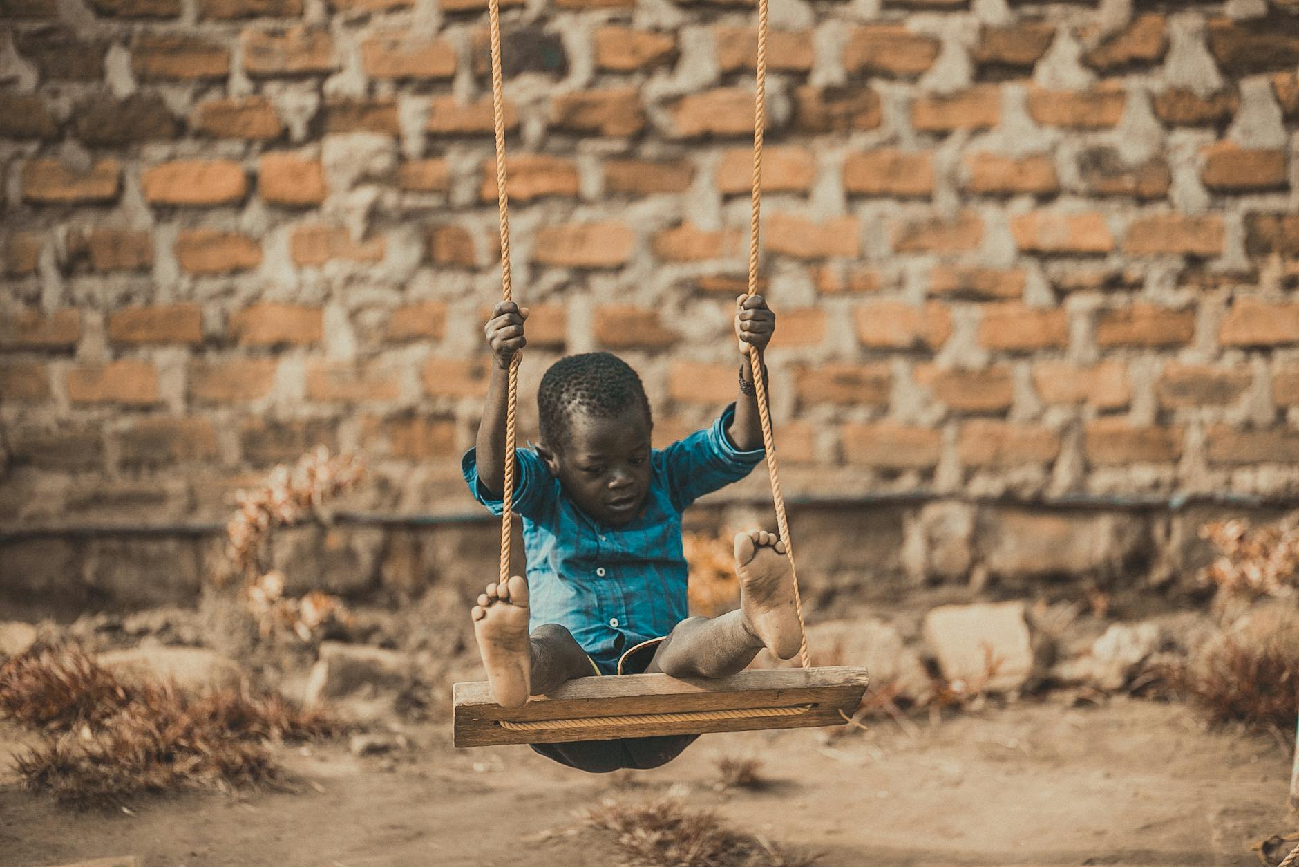 boy wearing blue shirt sitting on swing