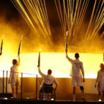 France’s Paralympic torchbearers hold the Paralympic flame in front of the Paralympic cauldron [Franck Fife/AFP]