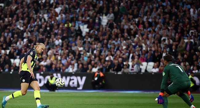 Manchester City’s Norwegian striker Erling Haaland (L) scores his third goal past West Ham United’s Polish goalkeeper Lukasz Fabianski at the London Stadium, in London on August 31, 2024. (Photo by HENRY NICHOLLS / AFP)