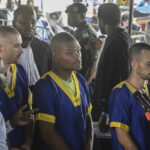 FILE PHOTO: Tyler Thompson Jr., Marcel Malanga and Benjamin Reuben Zalman-Polun, all American citizens, face the court in Kinshasa, Congo, with 52 other defendants, June 7, 2024, accused of a role in the attempted coup in Congo. © AP Photo / Samy Ntumba Shambuyi