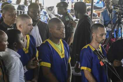 FILE PHOTO: Tyler Thompson Jr., Marcel Malanga and Benjamin Reuben Zalman-Polun, all American citizens, face the court in Kinshasa, Congo, with 52 other defendants, June 7, 2024, accused of a role in the attempted coup in Congo. © AP Photo / Samy Ntumba Shambuyi