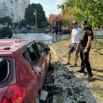 A local resident and a police officer stand at the site of a Russian missile strike in Kharkiv, Ukraine [Vitalii Hnidyi/Reuters]