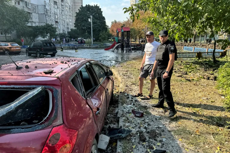 A local resident and a police officer stand at the site of a Russian missile strike in Kharkiv, Ukraine [Vitalii Hnidyi/Reuters]