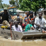 People affected by floods are escorted through flood water on a military boat in Maiduguri on September 12, 2024. (Photo by Audu MARTE / AFP)