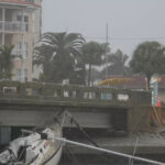 A boat damaged in Hurricane Helene rests against a bridge ahead of the arrival of Hurricane Milton, in South Pasadena, Fla.,