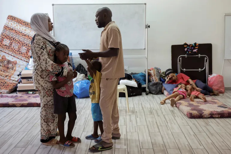 A family gathers at a women’s dormitory in the temporary shelter for migrants in Beirut, on October 1, 2024 [Louisa Gouliamaki/Reuters]