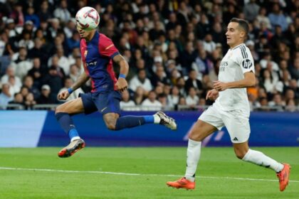 Barcelona’s Brazilian forward #11 Raphinha (L) scores his team’s fourth goal during the Spanish league football match between Real Madrid CF and FC Barcelona at the Santiago Bernabeu stadium in Madrid on October 26, 2024. (Photo by OSCAR DEL POZO / AFP)