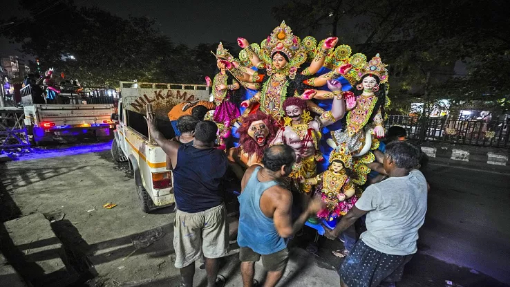 Artisans at a workshop carry a mud idol of the Hindu goddess Durga to load it on to a vehicle during the Durga Puja festival in Guwahati, India,