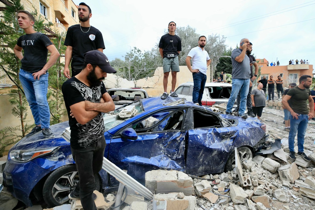 People inspect the damage at the site of an Israeli airstrike that targeted an apartment building in town of Barja south of Beirut on October 12, 2024. (Photo by Mahmoud ZAYYAT / AFP)