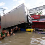 People wade through floods caused by Tropical Storm Trami in Naga in the Bicol region in central Philippines [Zalrian Sayat/AFP]