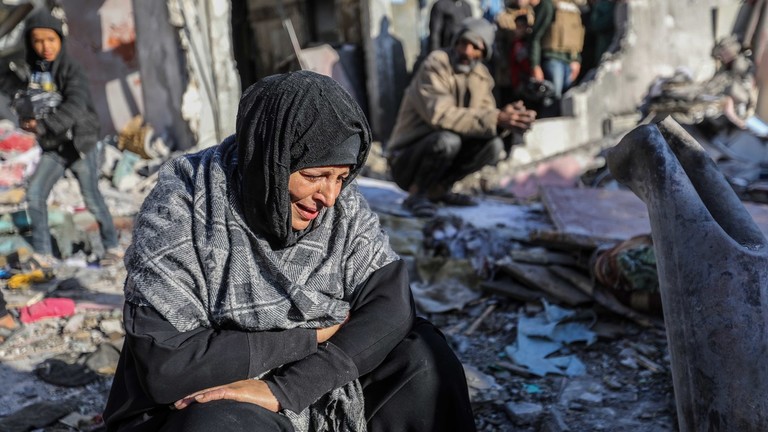 FILE PHOTO: A woman sits amongst damaged homes caused by Israeli air strikes, on January 18, 2024 in Rafah, Gaza. © Ahmad Hasaballah / Getty Images