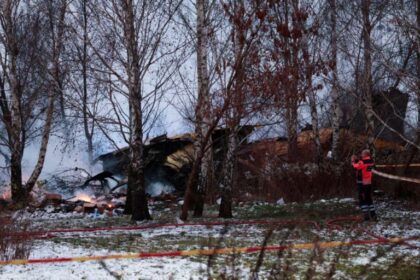 A Lithuanian medic takes a photo on his mobile phone of the wreckage of a cargo plane following its crash near the Vilnius International Airport in Vilnius on November 25, 2024. – A DHL cargo plane flying from Germany to Lithuania crashed early on November 25, 2024 near the airport of the capital Vilnius killing one person, firefighters said. (Photo by Petras Malukas / AFP)