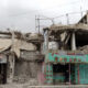 FILE PHOTO: A man buys from a shop located in a building destroyed in past aerial strikes in Sana'a, Yemen. © Mohammed Hamoud / Getty Images