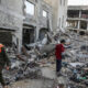 Children walk past destroyed buildings in Khan Yunis, Gaza on December 10, 2024. © Abed Rahim Khatib / Anadolu / Getty Images