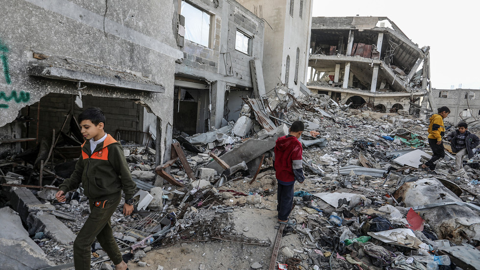 Children walk past destroyed buildings in Khan Yunis, Gaza on December 10, 2024. © Abed Rahim Khatib / Anadolu / Getty Images