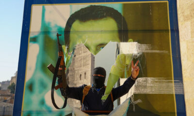 Jihadist militant tearing down a poster of Syrian Presdient Bashar Assad in Aleppo, Syria, November 30, 2024. © Getty Images / Rami Alsayed/NurPhoto