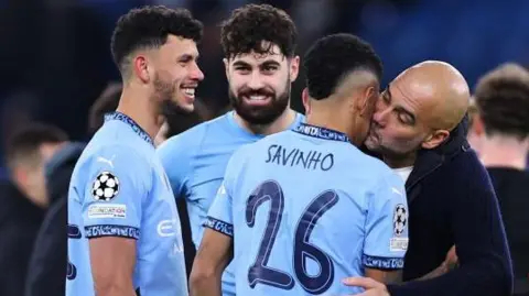 Manchester City manager Pep Guardiola plants a kiss on Savinho after his goal helped them into the Champions League play-offs with victory over Club Brugge