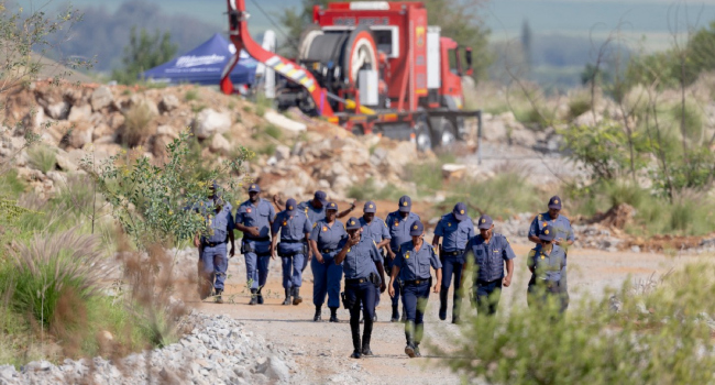 South African Police Service (SAPS) officers walk near a Metalliferous Mobile Rescue Winder during a rescue operation to retrieve illegal miners from an abandoned gold shaft in Stilfontein on January 13, 2025. (Photo by Christian Velcich / AFP)