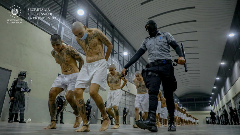 FILE PHOTO. Inmates belonging to the MS-13 and Barrio 18 gangs arrive to the Terrorist Confinement Center (CECOT) in Tecoluca, El Salvador. © Getty Images / Anadolu Agency / Press Secretary Of The Presidency Of El Salvador