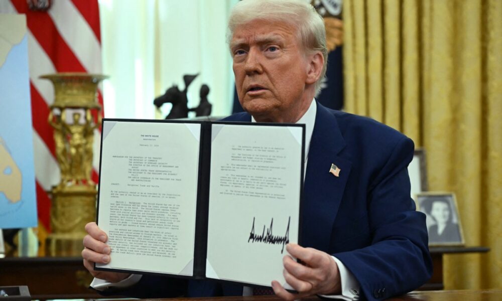 US President Donald Trump displays his signature on an Executive Order on reciprocal tariffs in the Oval Office of the White House in Washington, DC, on February 13, 2025. (Photo by ANDREW CABALLERO-REYNOLDS / AFP)